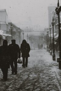 Moody black and white image of a snowy street in Eskişehir, Türkiye with silhouetted figures.